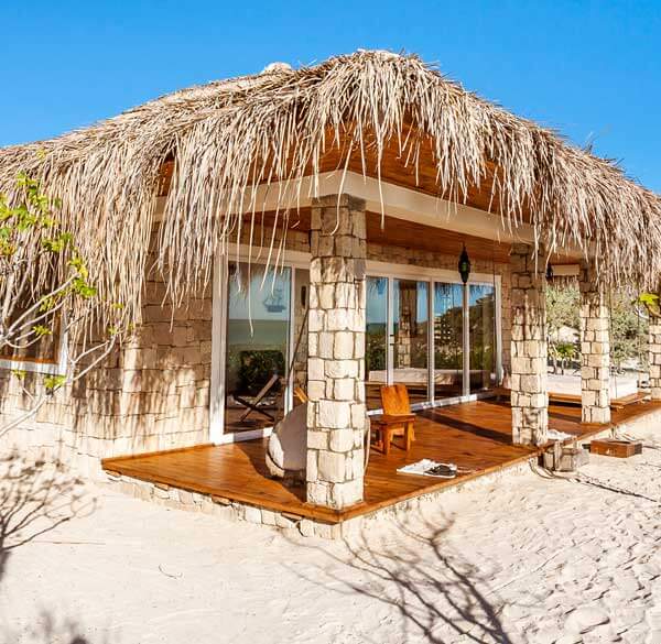Bungalow en pierre au toit végétal en bord de plage